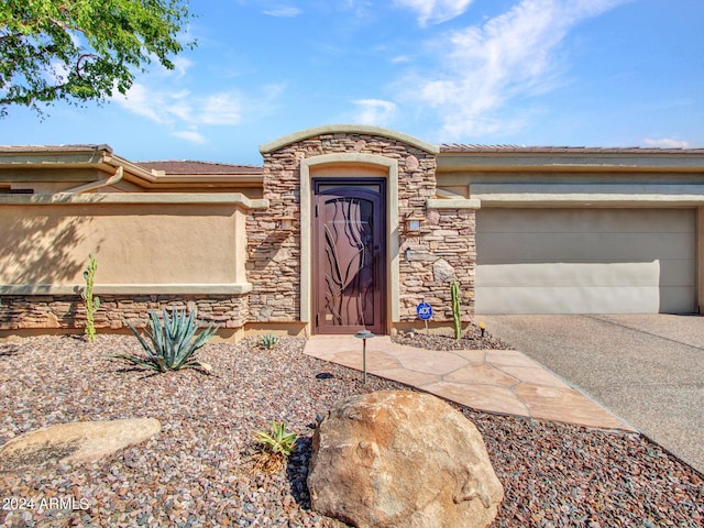 3220 W Feather Sound Dr, Anthem, AZ 85086 - property entrance with a tiled roof, an attached garage, stone siding, concrete driveway, and stucco siding