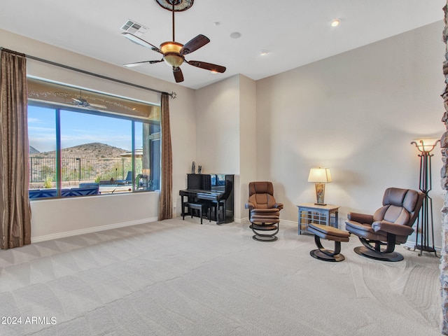 living area featuring a mountain view, ceiling fan, and carpet flooring