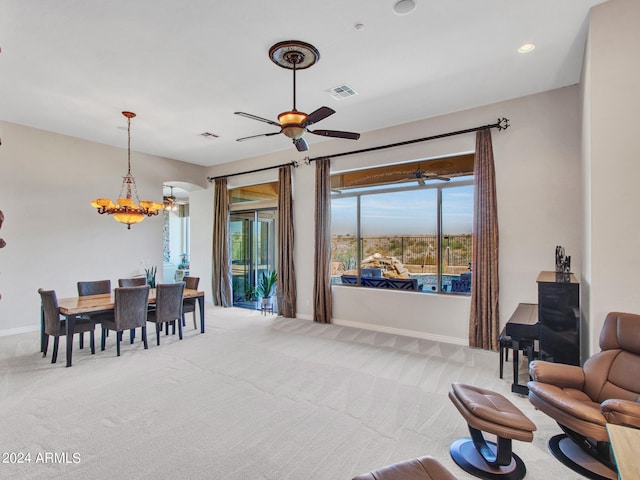 carpeted living room with ceiling fan with notable chandelier