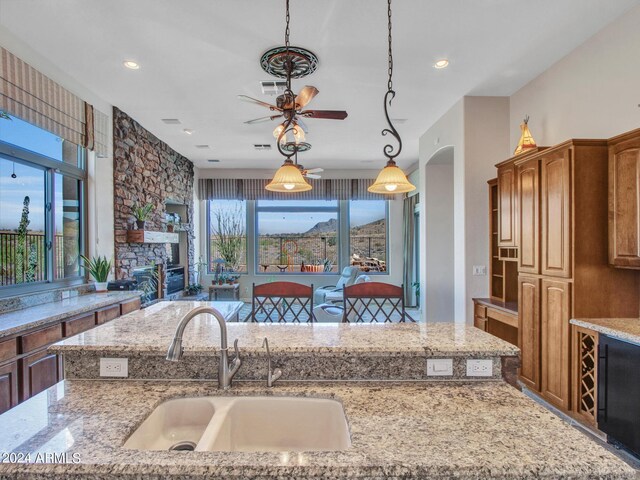 3220 W Feather Sound Dr, Anthem, AZ 85086 - kitchen featuring a stone fireplace, a sink, a ceiling fan, and light stone countertops