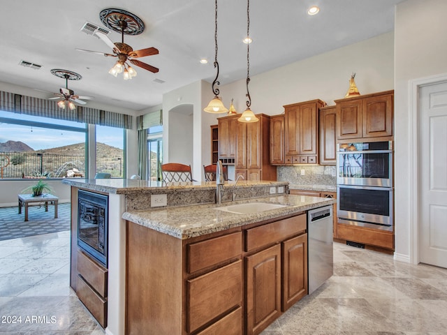 kitchen with sink, an island with sink, appliances with stainless steel finishes, decorative light fixtures, and ceiling fan