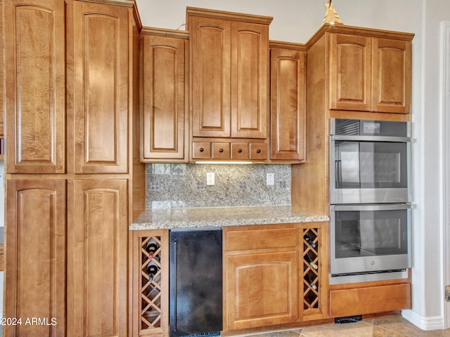 kitchen with light stone counters, double oven, light tile patterned floors, and decorative backsplash