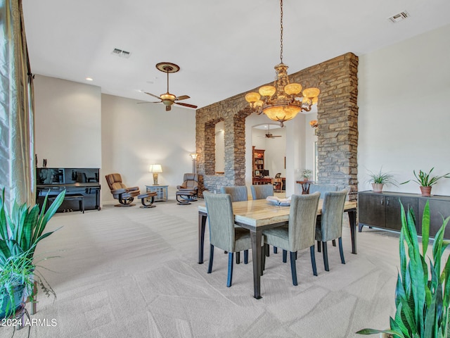 dining area featuring light colored carpet and ceiling fan with notable chandelier