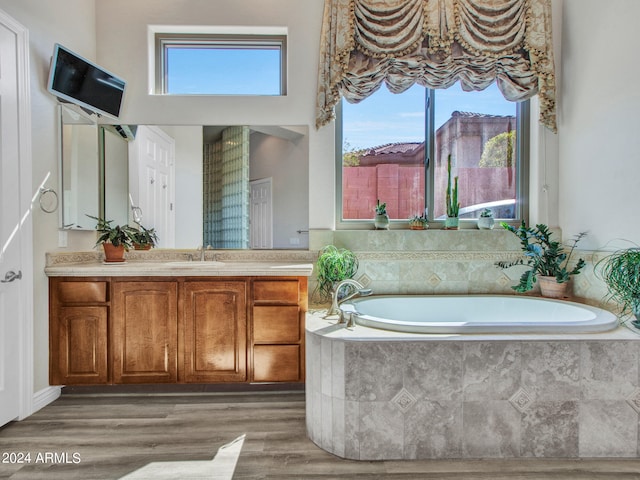 bathroom featuring a relaxing tiled tub, vanity, and hardwood / wood-style flooring