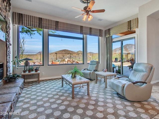 carpeted living room featuring a healthy amount of sunlight, ceiling fan, and a mountain view