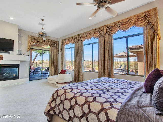 carpeted bedroom with ceiling fan, a multi sided fireplace, access to exterior, and multiple windows