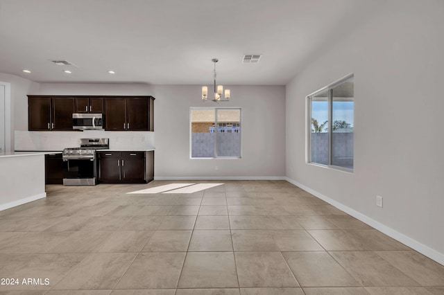 kitchen featuring appliances with stainless steel finishes, hanging light fixtures, light tile patterned floors, dark brown cabinetry, and an inviting chandelier