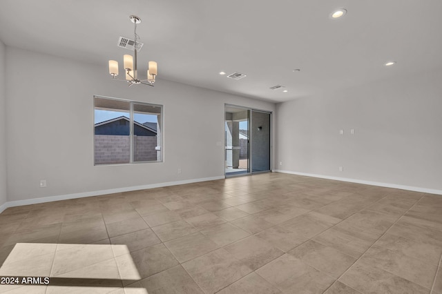 spare room featuring a wealth of natural light, a notable chandelier, and light tile patterned floors