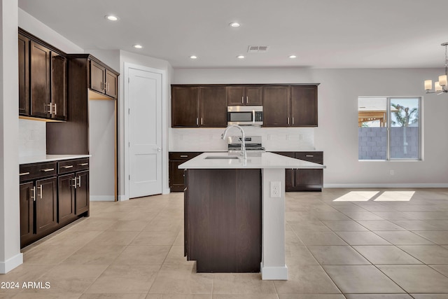 kitchen featuring sink, dark brown cabinets, stainless steel appliances, decorative backsplash, and decorative light fixtures