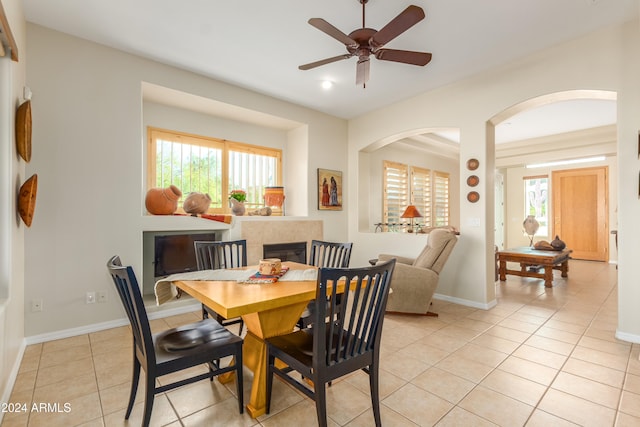 tiled dining area with ceiling fan, plenty of natural light, and a tile fireplace