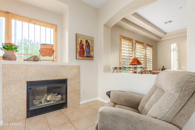 living area featuring a tiled fireplace, light tile patterned floors, and plenty of natural light