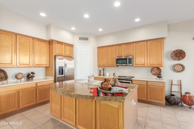 kitchen featuring appliances with stainless steel finishes, sink, light tile patterned floors, and an island with sink