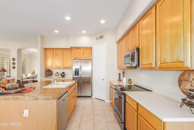 kitchen with a kitchen island with sink, stainless steel appliances, sink, light tile patterned floors, and light brown cabinetry