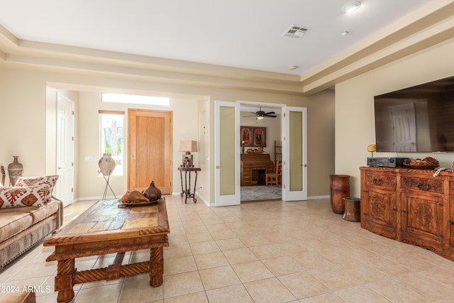 living room with light tile patterned flooring, a tray ceiling, and ceiling fan