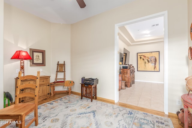 living area with tile patterned flooring, a tray ceiling, and ceiling fan
