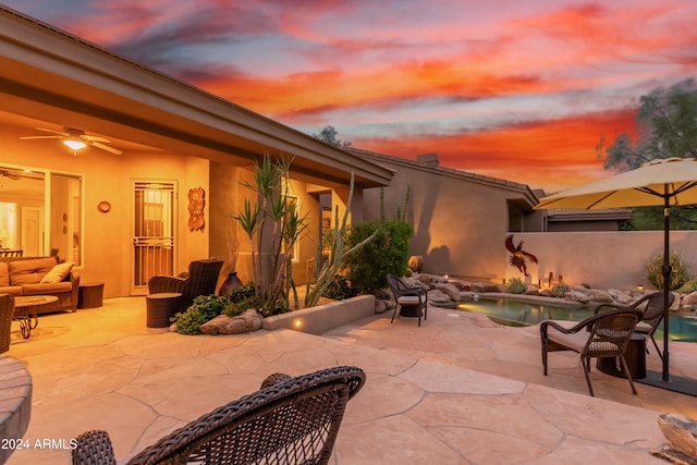 patio terrace at dusk with an outdoor living space, a fenced in pool, and ceiling fan