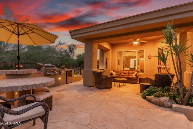 patio terrace at dusk featuring an outdoor living space, area for grilling, and ceiling fan