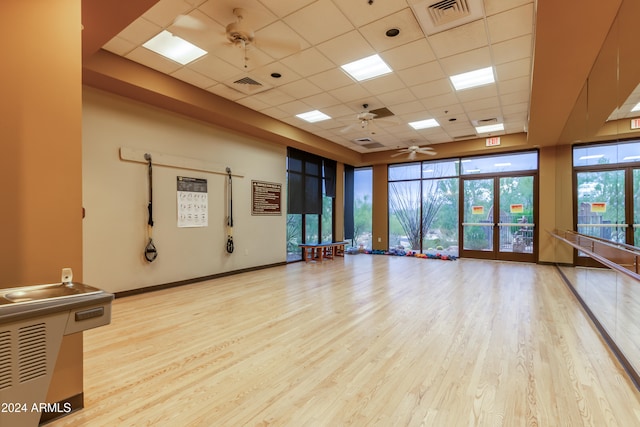 exercise area featuring a drop ceiling, light hardwood / wood-style flooring, french doors, and ceiling fan
