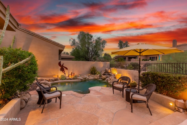 pool at dusk with a patio area