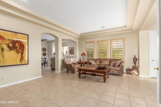 living room featuring a tray ceiling and light tile patterned floors
