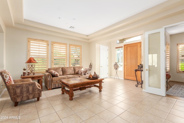 living room featuring a raised ceiling, light tile patterned floors, and plenty of natural light