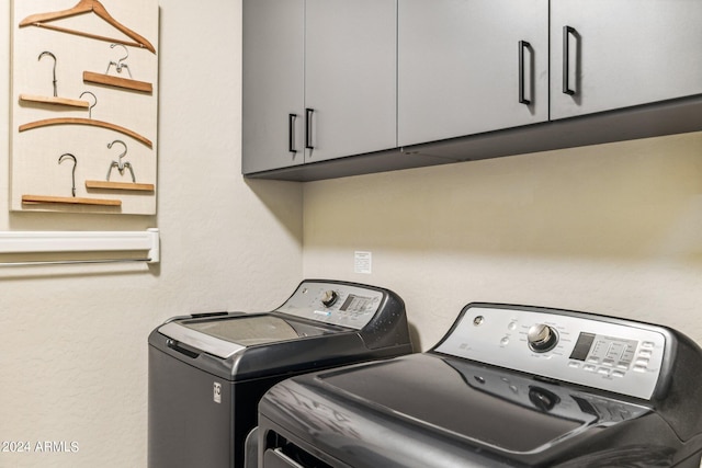 clothes washing area featuring washing machine and clothes dryer and cabinets