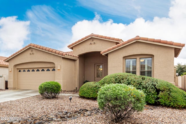 mediterranean / spanish-style home with stucco siding, an attached garage, fence, driveway, and a tiled roof