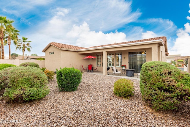 back of property featuring a tile roof, a patio area, fence, and stucco siding