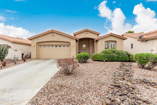 mediterranean / spanish-style home with driveway, an attached garage, a tiled roof, and stucco siding