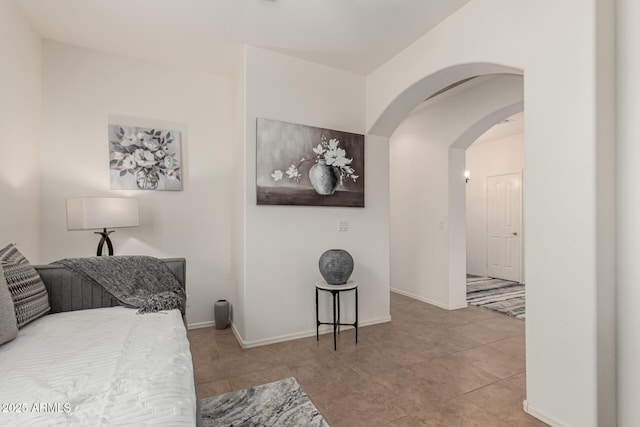 tiled bedroom with arched walkways and baseboards