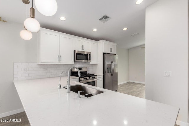 kitchen featuring stainless steel appliances, light countertops, decorative backsplash, light wood-style floors, and a sink