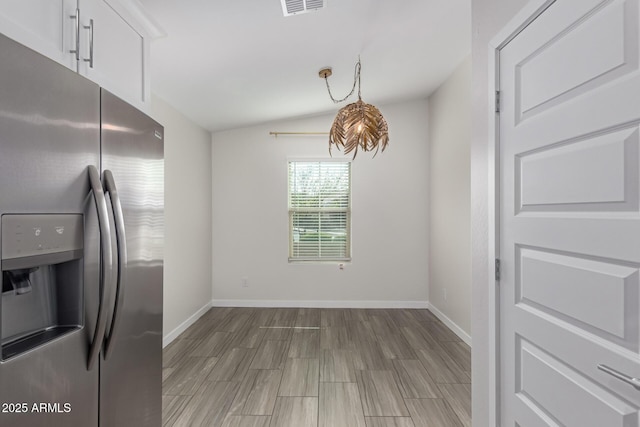 unfurnished dining area with vaulted ceiling and baseboards