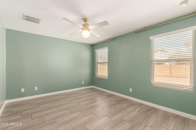 spare room with ceiling fan, visible vents, and baseboards