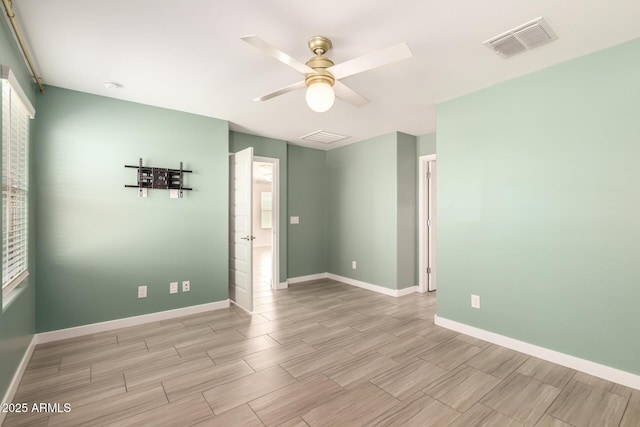 spare room featuring baseboards, wood tiled floor, visible vents, and ceiling fan