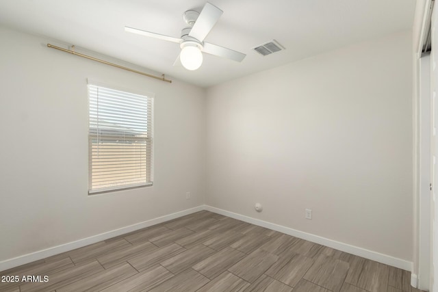 unfurnished room with wood tiled floor, visible vents, ceiling fan, and baseboards