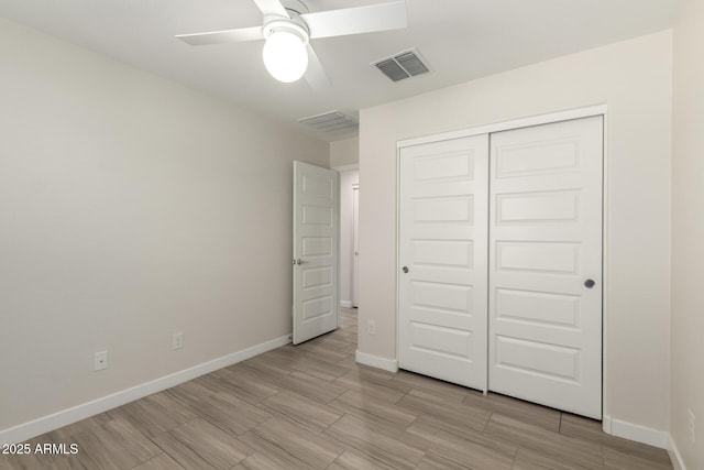 unfurnished bedroom featuring baseboards, wood tiled floor, visible vents, and a closet