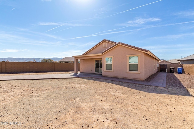 back of property with a mountain view, a fenced backyard, a patio, and stucco siding