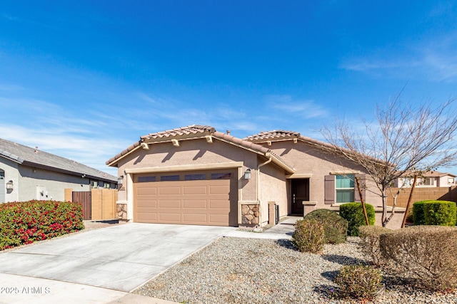 view of front of property with stucco siding, concrete driveway, an attached garage, fence, and a tiled roof