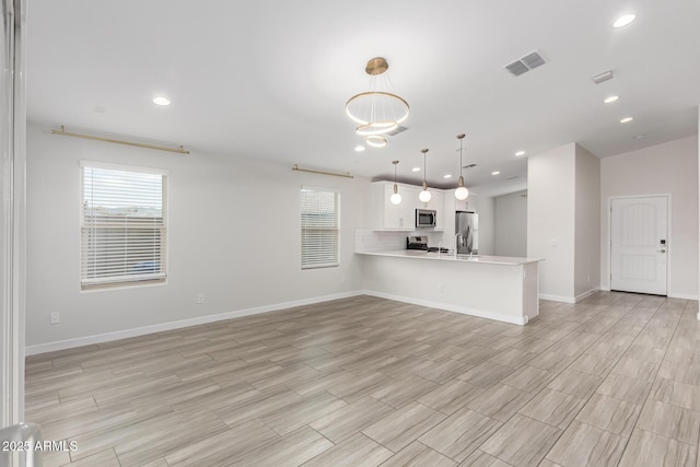 unfurnished living room with baseboards, visible vents, a wealth of natural light, and recessed lighting