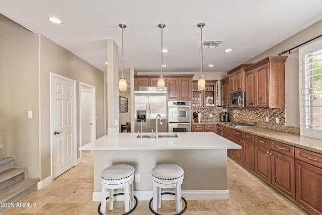 6847 S 27th Pl, Phoenix, AZ 85042 - kitchen with a sink, stainless steel appliances, a center island with sink, tasteful backsplash, and brown cabinets