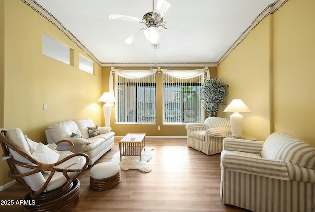 living area with a wealth of natural light, baseboards, wood finished floors, and ornamental molding