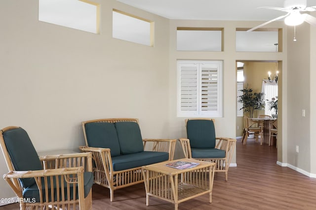 sitting room featuring ceiling fan with notable chandelier, baseboards, and wood finished floors