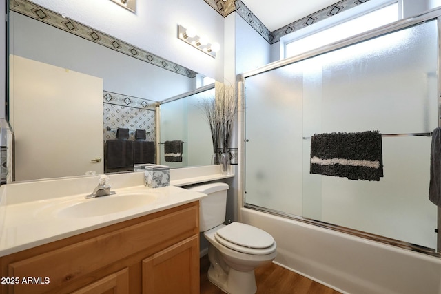 bathroom with enclosed tub / shower combo, toilet, wood finished floors, and vanity