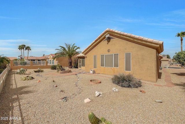 back of house with stucco siding, a tile roof, and fence