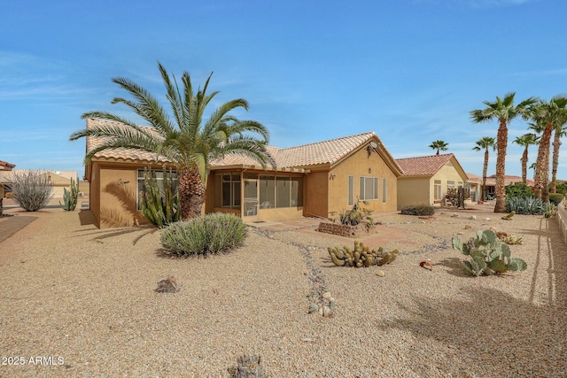 view of front of house with a tiled roof, stucco siding, and a sunroom