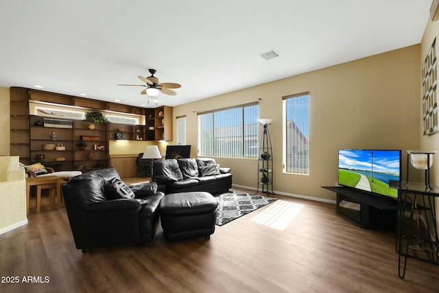 living area with a ceiling fan, wood finished floors, visible vents, and baseboards