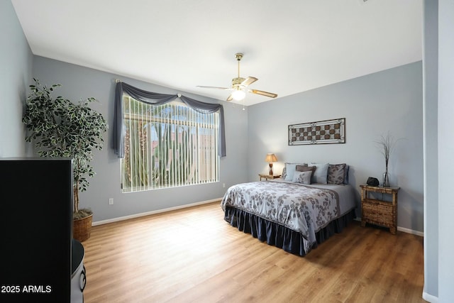 bedroom with a ceiling fan, wood finished floors, and baseboards