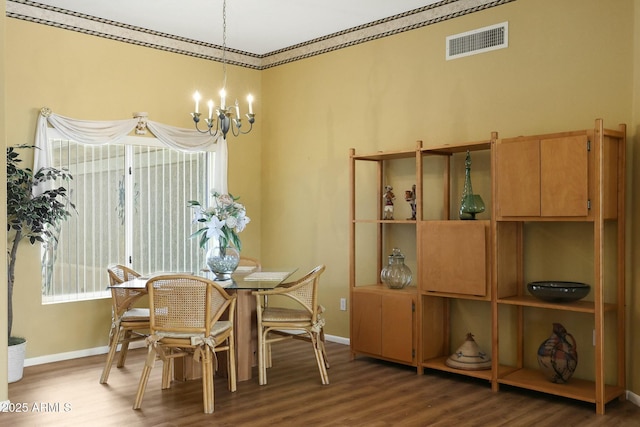 dining space featuring visible vents, baseboards, an inviting chandelier, and wood finished floors