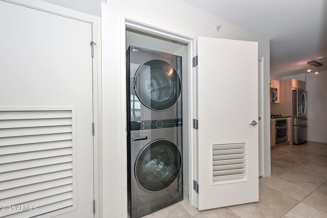 washroom with stacked washer / drying machine and light tile patterned floors