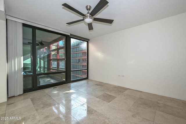 empty room with ceiling fan and expansive windows